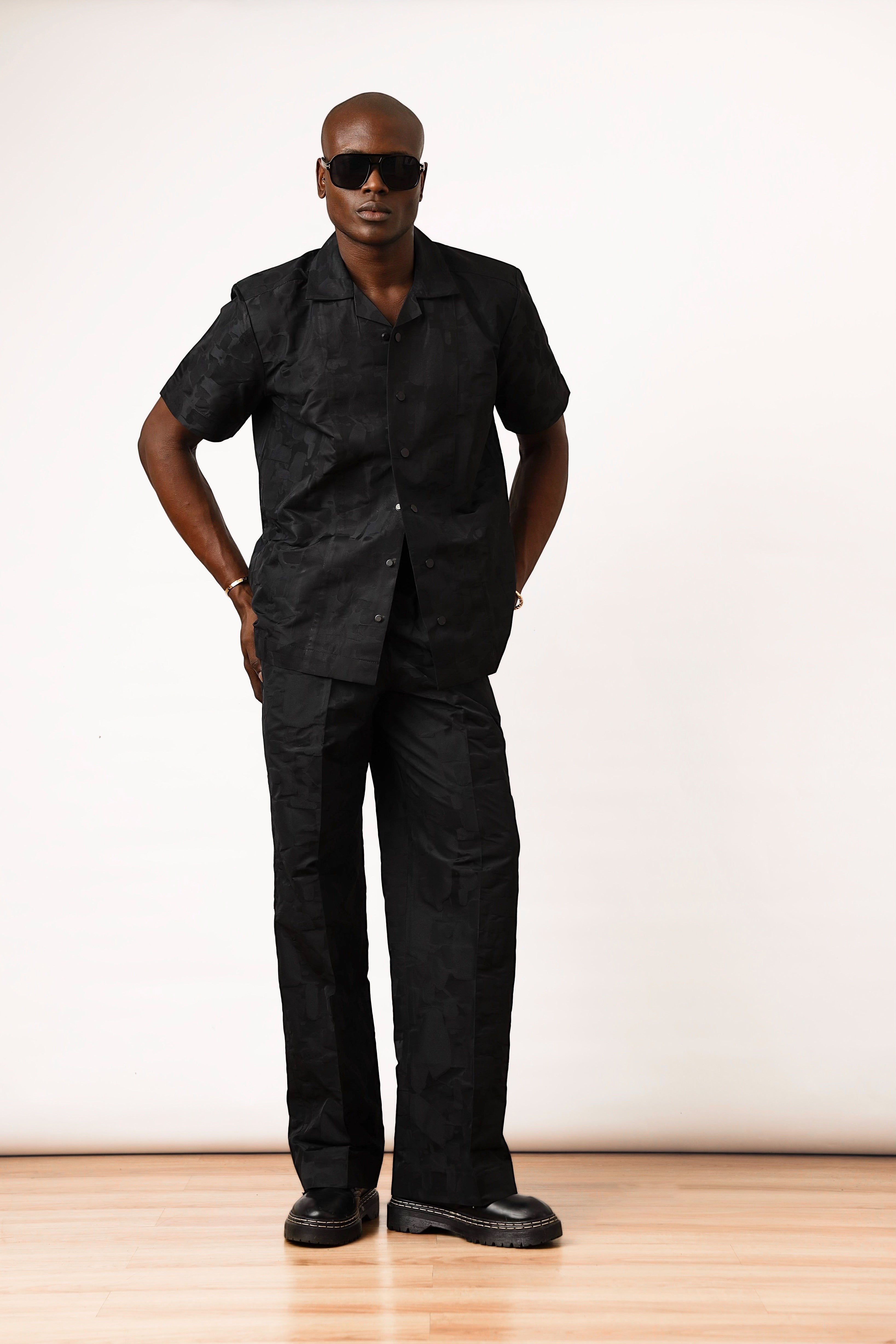 Shop Frugal black brocade Cuban shirt with short sleeves and dual patch pockets, worn by a man with sunglasses.